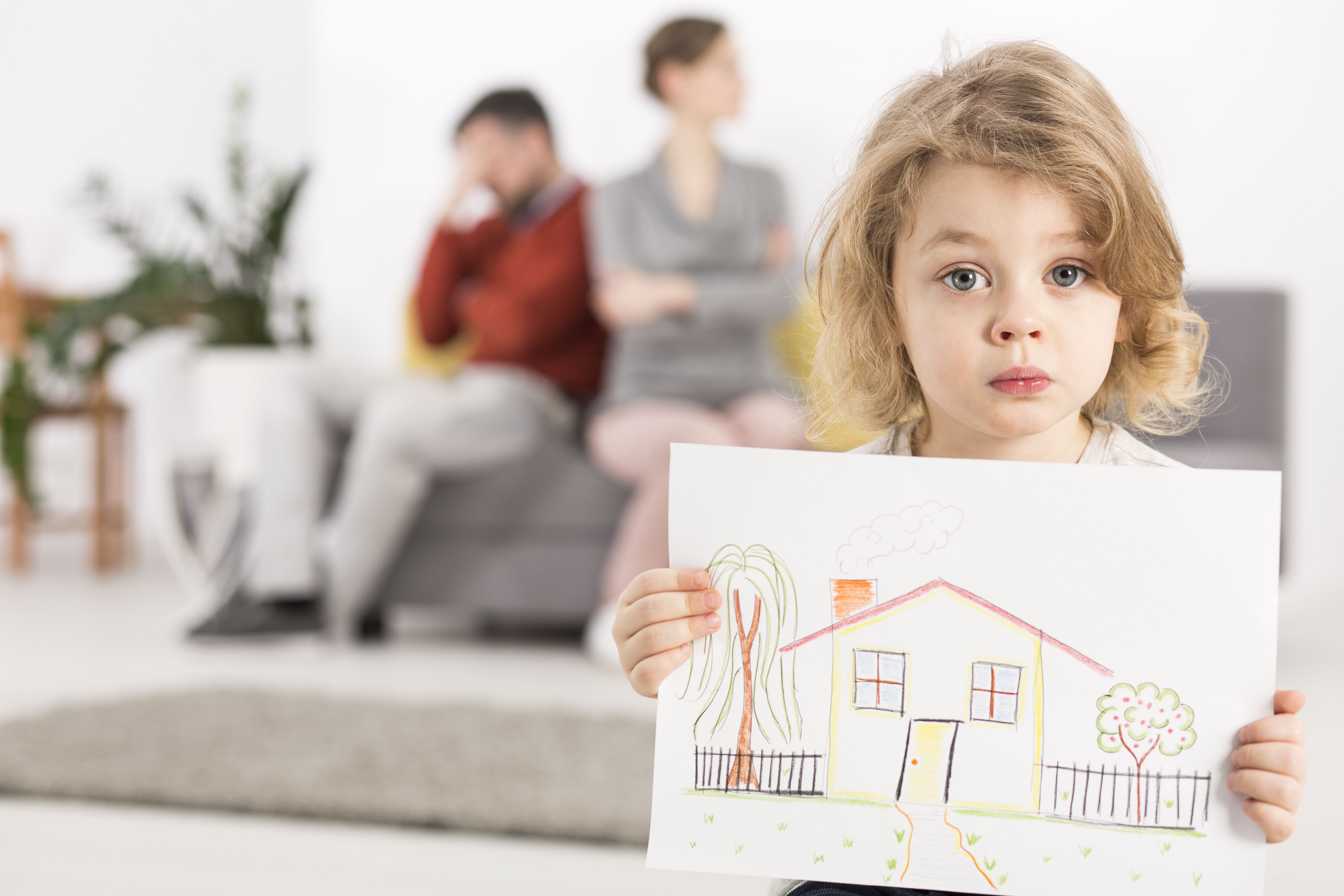 young girl holding drawing of house